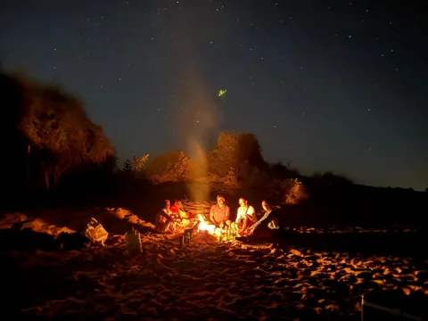 A campfire lighting the sand at night