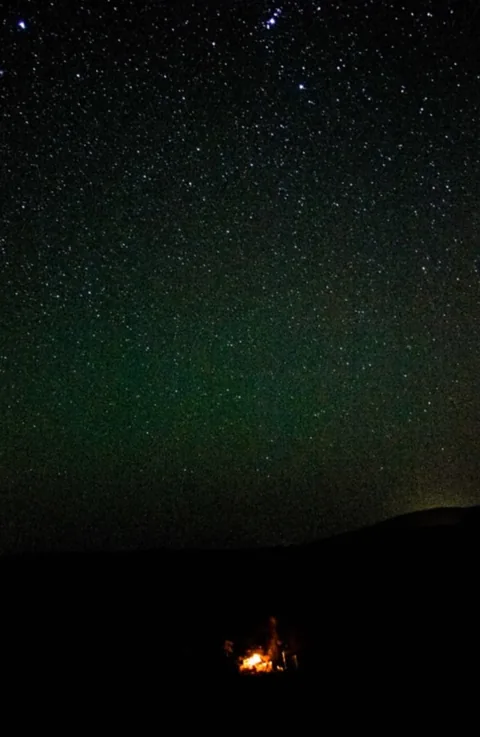 Stars above a horizon with a soft green glow