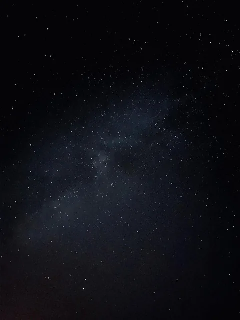A band of stars above a dark desert horizon