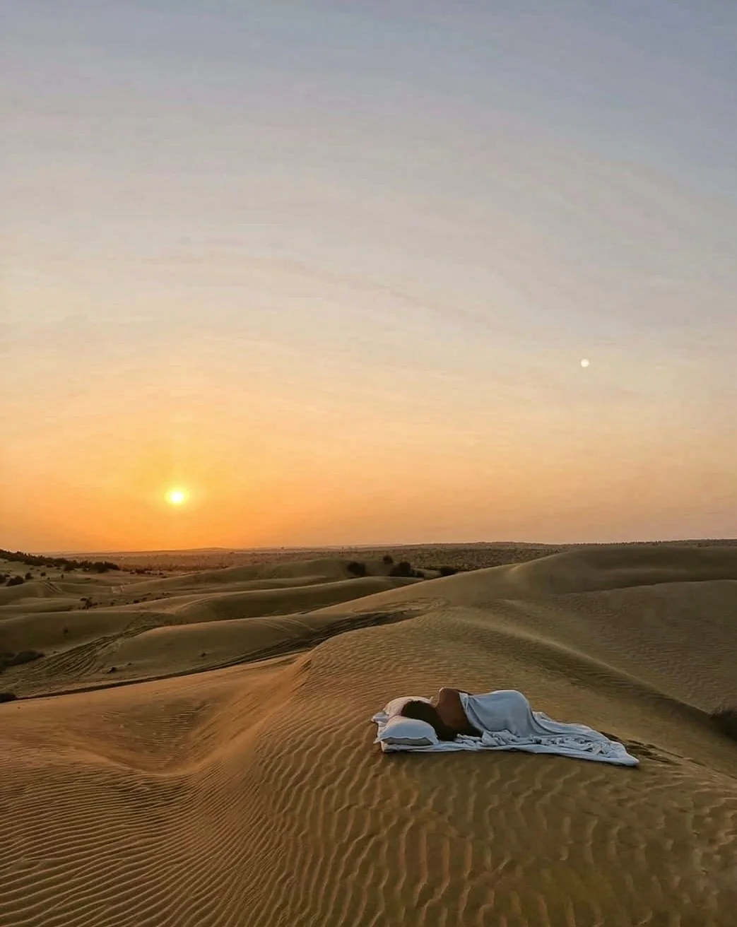 Sun setting over desert dunes and overnight bedding
